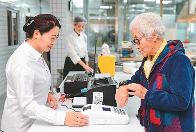  一位老人在内蒙古自治区鄂尔多斯市康巴什区神华康城社区“邻里食堂”使用智能积分刷卡器用餐。王 正摄（人民视觉）