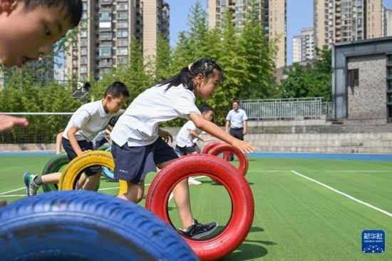 5月19日，重庆市渝中区天地人和街小学，同学们参加滚轮胎大课间活动。新华社记者 陈诚 摄