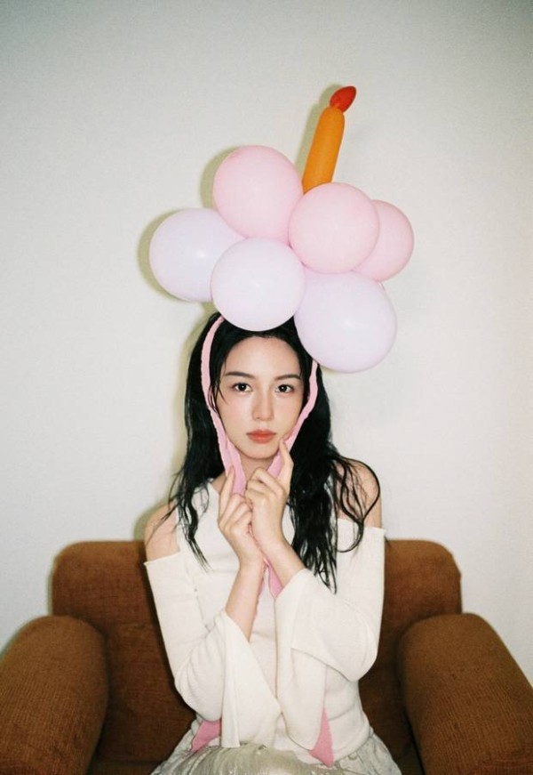 周也身着粉色条纹衬衫，头戴气球宛如梦幻少女
