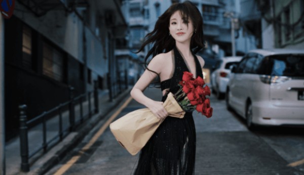 祝绪丹手拿玫瑰站在街边,发丝随风飘扬。