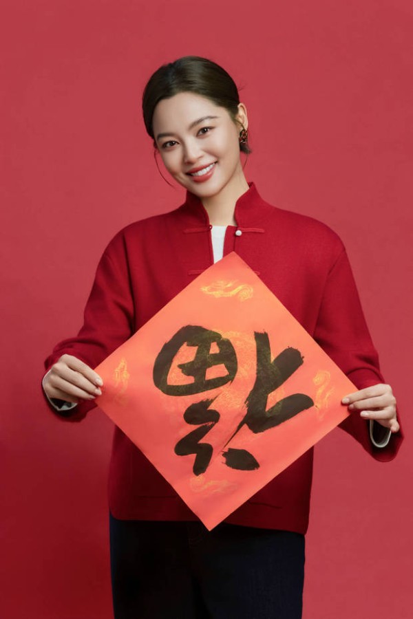 辛芷蕾双手举着福字，笑容灿烂。