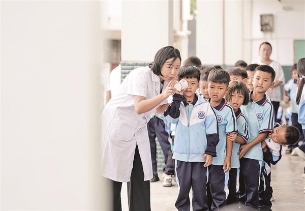 云南孟连县公信乡卫生院工作人员在戈的小学指导学生们进行视力筛查。新华社发